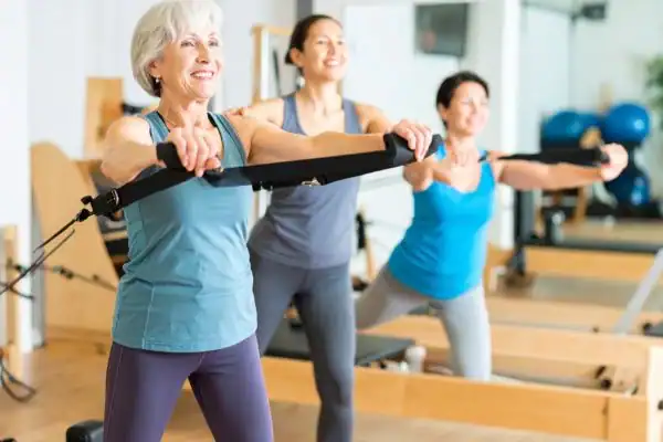 Toning Arms After 60: Empowering Womens Fitness Through Effective Weight Training 2 older woman doing weight training Cranleigh and resistance in the gym to tone upper arms