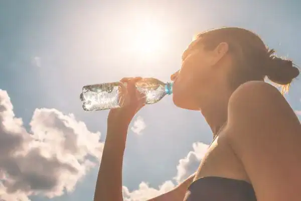 Hydration: The Secret Ingredient for a Toned Stomach and Enhanced Fitness 3 Image of woman drinking water to hydrate Cranleigh after run.