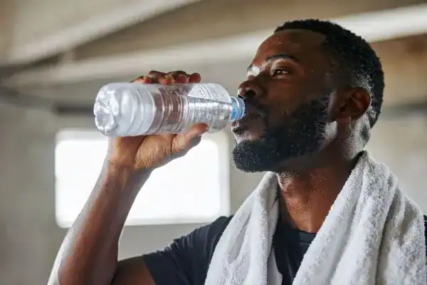 Hydration: The Secret Ingredient for a Toned Stomach and Enhanced Fitness 1 Image of man drinking water to improve hydration Cranleigh after work out.